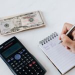 crop anonymous financier planning budget writing numbers in notebook